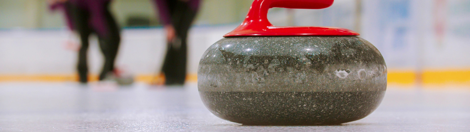 Curling - a granite stone with red handle on the ice field