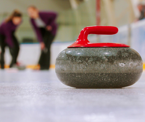 Curling - a granite stone with red handle on the ice field